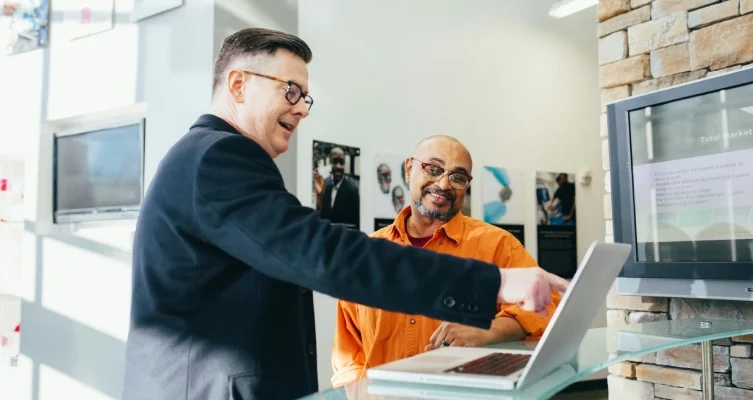 two men discussing inventory management for small businesses at a laptop.