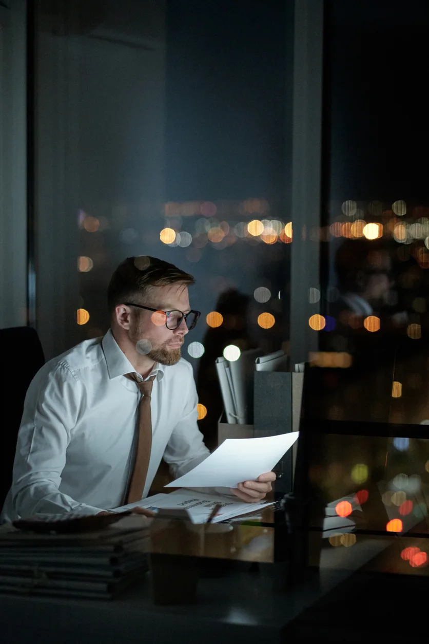 man sitting at his computer ,late in the evening analysing business information.